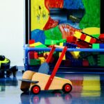 Speelhoek met grote bouwblokken, een houten loopwagen en speelgoedvoertuigen in een ingerichte woning voor kinderopvang