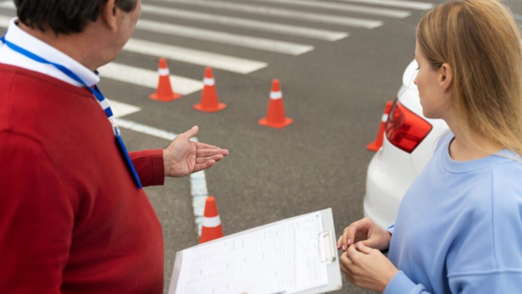 Instructeur begeleidt leerling tijdens motorrijles Tilburg op oefenterrein met pylonen en lesauto