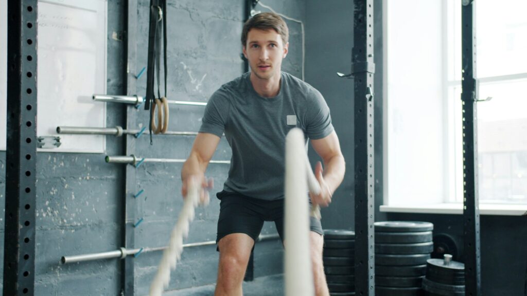 Man traint met battle ropes in de sportschool voor het verbeteren van zijn basisconditie