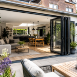 Moderne woning met ruime aanbouw, open glazen schuifpuien en lichte leefruimte die naadloos overloopt in een groene tuin